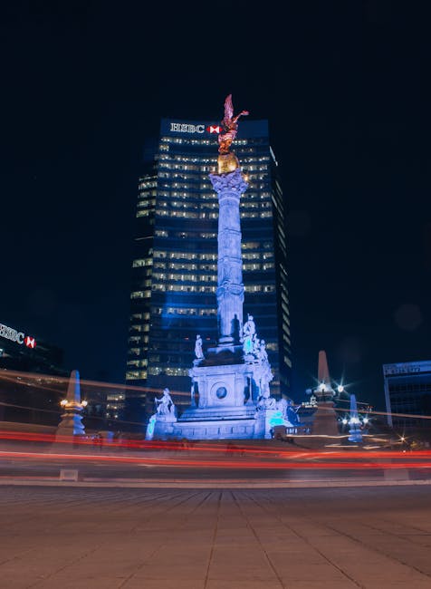 Night view of the Angel of Independence in Mexico City with light trails and illuminated buildings.
